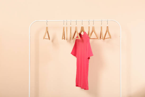 istock empty clothes hangers on a wardrobe rack on a colored background. 1279620079