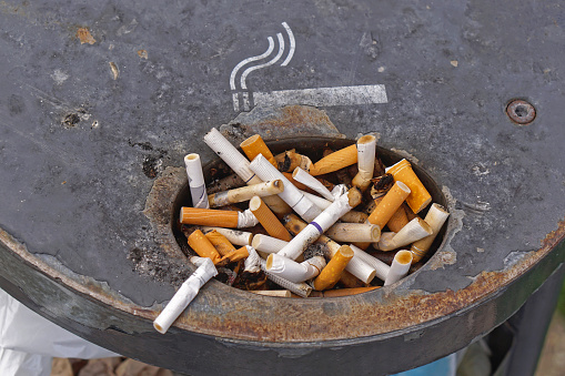 Discarded cigarette butts in overloaded ashtray