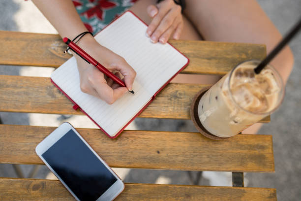 istock Woman taking notes on a notebook and drinking ice latte at cafe 1279627354