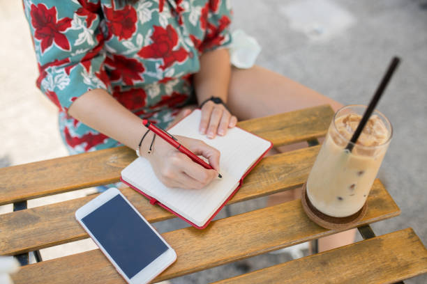 istock Woman taking notes on a notebook and drinking ice latte at cafe 1279627362