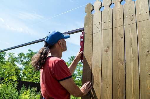 A man builds a wooden fence.