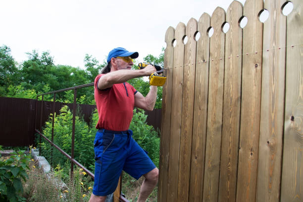 A man builds a wooden fence.