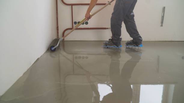istock A worker rolls out the liquid floor with a trowel. Squeegee for distributing the mixture. The worker levels the liquid floor. Finishing works - Needle roller for bulk floor 1279637530