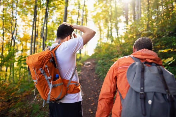 istock Two hikers in the forest moving up, while one is using a camera and taking a photo of nature 1279638444