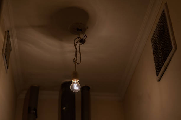electrical light bulb hangs on long cable in toilet room of cheap hostel indoor