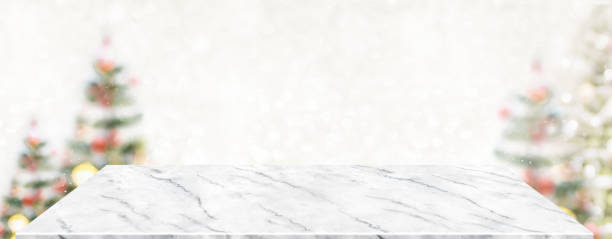 istock Perspective marble table with blur Christmas tree decorate string light and blue bokeh with snow light.Panoramic wooden countertop banner mock up for product display greeting card design online content 1279638566