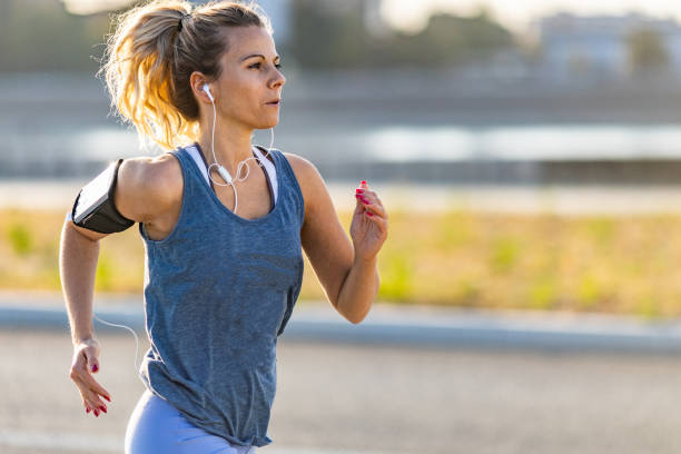 istock Young woman listening music while jogging 1279643765
