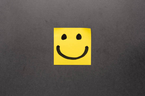 Drawing of a happy smiling emoticon on a yellow paper and black background Drawing of a happy smiling emoticon on a yellow paper and black background smiley face postit stock pictures, royalty-free photos & images