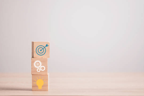 Achievement business target concept ,  Stacking wooden cubes block which print screen target , mechanical gear , light bulb.