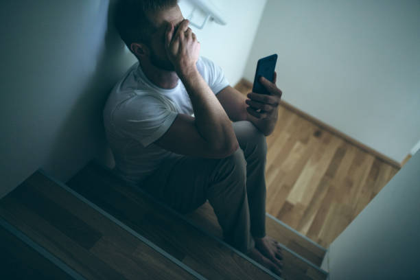 hombre deprimido sentado en la oscuridad - men mental illness loss despair fotografías e imágenes de stock