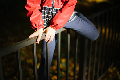 Young boy climbing over a fence on an early morning sunrise