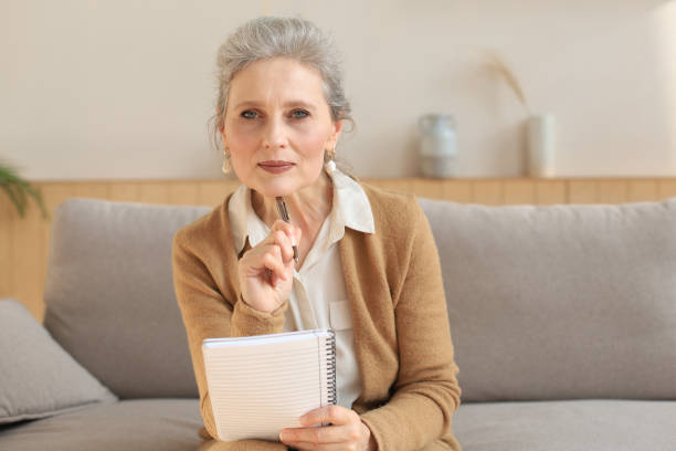 istock Attractive mature woman sitting on the couch and making notes in diary. 1279648868