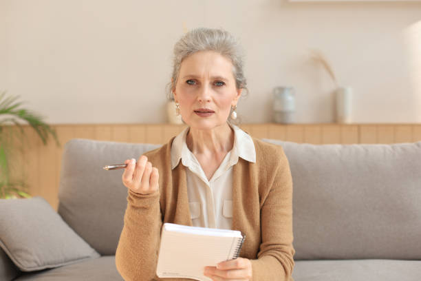 istock Attractive mature woman sitting on the couch and making notes in diary. 1279649091