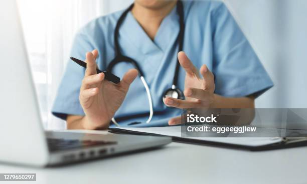 Surgeon Female Doctor Making Video Call Meeting With Physician Team On Laptop Stock Photo - Download Image Now