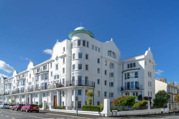 Hastings, UK-June 2, 2024; Row of  characteristic white houses on top of West Hill with in front campervan and folding camping chairs with fabric of British flag in green grass