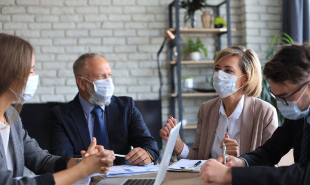 istock Business people wearing protective face masks while holding a presentation on a meeting during coronavirus epidemic. 1279650519