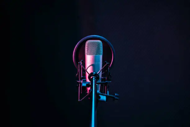 Photo of Studio microphone and pop shield on mic in the empty recording studio with copy space. Performance and show in the music business equipment.