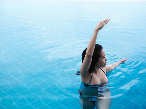 beautiful professional asian woman practice aqua yoga water therapy side bend twist pose balance in swimming pool body mind spirit spiritual healing