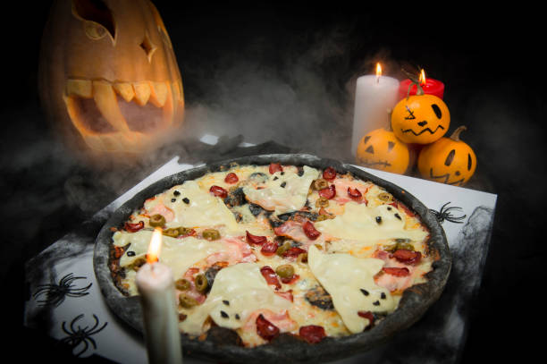 istock Halloween ghost pizza served on delivery box. Bat, spiders, candles and painted pumpkins decor. 1279654573