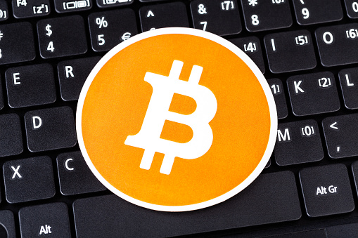 One orange bitcoin logo, circle symbol laying on black modern pc laptop netbook computer keyboard, crypto currency e-commerce simple finance concept. Single minimal cryptocurrency icon