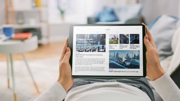 istock Young Woman at Home Lying on a Couch Using Tablet Computer in Horizontal Landscape Mode for Reading Technology News. Girl Using Touchscreen Device, Browsing Internet, Blogs. POV Shot. 1279660373