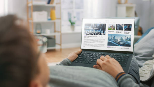 istock Young Man at Home Laying on a Couch and Using Laptop Computer for Reading News about Technological Breakthroughs. Guy is Using Laptop Device, Browsing Internet, Watching Content, Videos. 1279660380