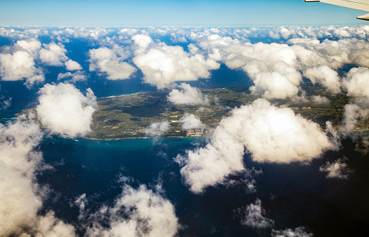 Shot from an airplane on a bright sunny day with billowy, white, cumulus clouds over the Caribbean island of Barbados.