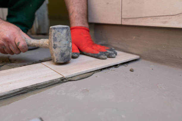 istock A worker laying ceramic tiles in the bathroom with a rubber mallet gently aligns the floor plane. 1279663398