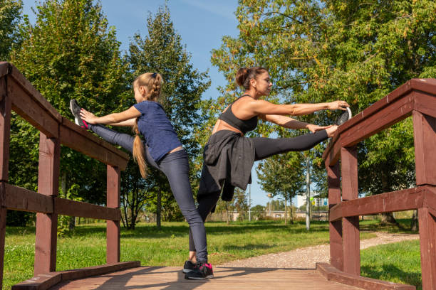 istock Mother and daughter stretching legs together 1279667174