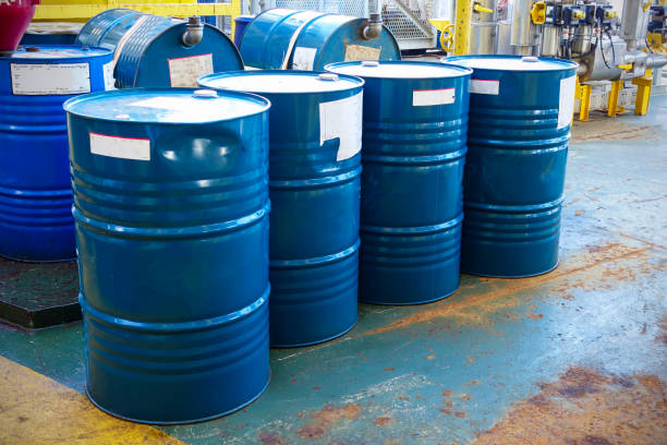 Blue oil drums in front of a factory or industrial plant for oil and gas industry concept. stock photo
