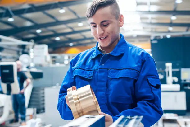 Apprentice in metalworking looking at workpiece being satisfied