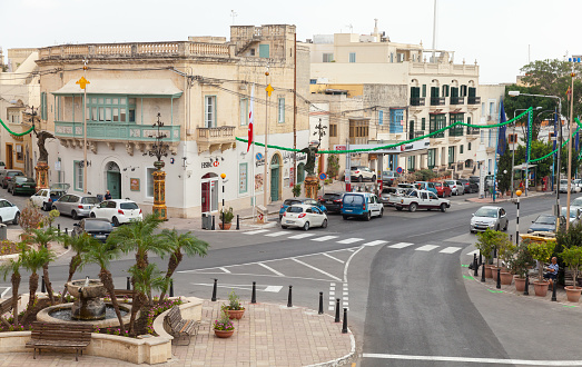 In-Naxxar, Malta - August 31, 2019: Street view of Triq Tal-Labour with street fountain, parked cars and ordinary people an the street