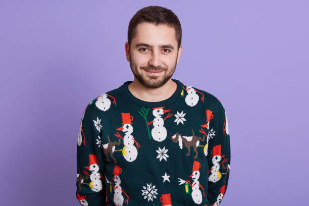 istock Funny winter man in warm clothes posing isolated over lilac wall, looking smiling directly at camera, bearded young guy with calm expression and smile. 1279673721