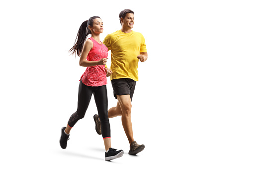 Full length shot of a young man and woman in sportswear jogging isolated on white background