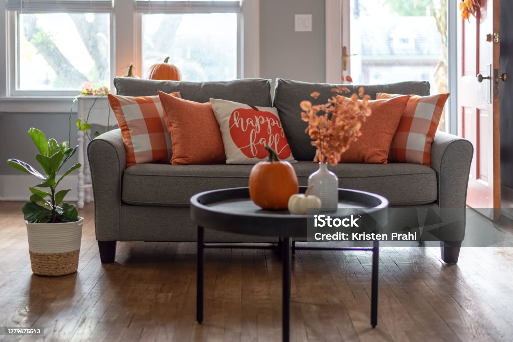 Home interior decorated for fall with orange accent pillows on the sofa Happy fall throw pillow on the sofa for autumn season home decor Autumn Stock Photo
