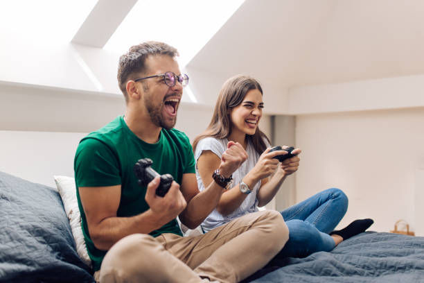 istock Young man cheering while playing a video game against his girlfriend 1279675747