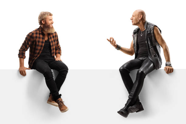 istock Young bearded man talking to a punk, both sitting on a blank panel 1279677918