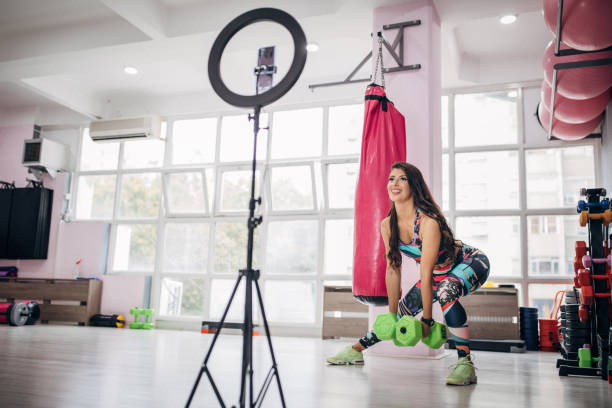 istock Beautiful fit woman recording online tutorial for weightlifting training in gym 1279677935