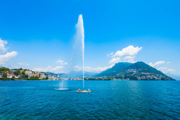 Fountain at Lugano lake and Lugano city panoramic view in canton of Ticino in Switzerland