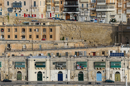 The ancient cityscape of Valletta in Malta with colourful doors and window frames and multiple levels of housing and commercial buildings
