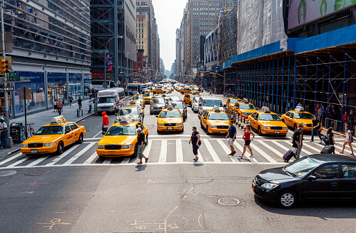 New York, United States - September 4, 2011: Pedestrians crossing the street in Midtown Manhattan, cars standing at traffic light
