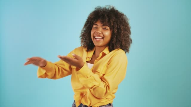 Dark-skinned female laughing and showing waisting or throwing money around hand gesture, posing against blue background