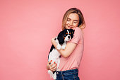 Studio portrait of smiling young woman holding little dog
