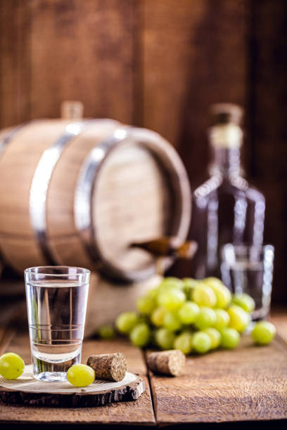 szklanka brandy na bazie winogron, zwana bagaceira w portugalii i we włoszech grappa lub graspa, z dębową beczką w tle - vodka hard liquor bottle palinka zdjęcia i obrazy z banku zdjęć