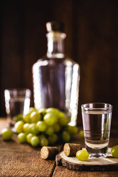 szklanka brandy na bazie winogron, zwana bagaceira w portugalii i we włoszech grappa lub graspa, z dębową beczką w tle - vodka hard liquor bottle palinka zdjęcia i obrazy z banku zdjęć