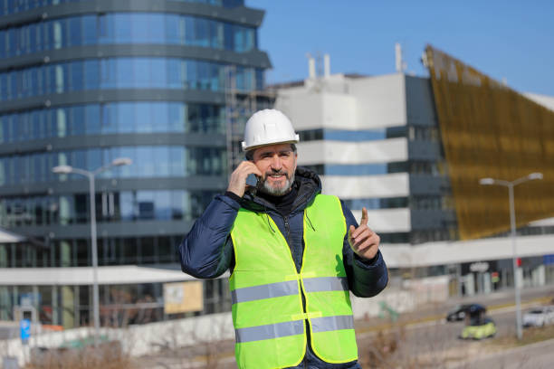 istock Cheerful engineer holding blueprint and talking on mobile phone on construction site 1279702511