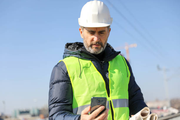 スマートフォンを使用した建設現場のエンジニア - corporate business manager manual worker architect ストックフォトと画像