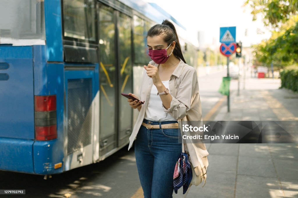 Portrait of a young woman wearing protective face mask waiting for the bus Waiting Stock Photo