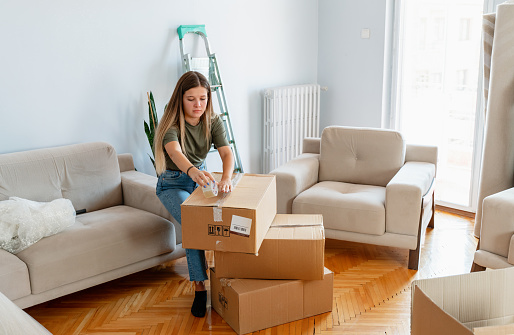 young woman opening boxes in her new home