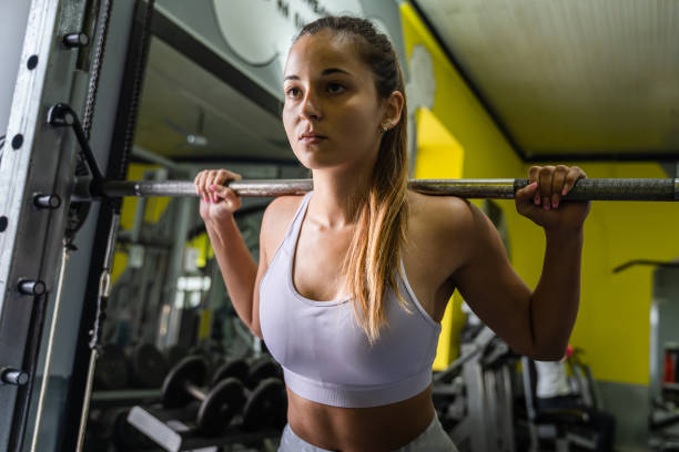 istock Young caucasian woman training at gym with barbell weights doing squats 1279705567